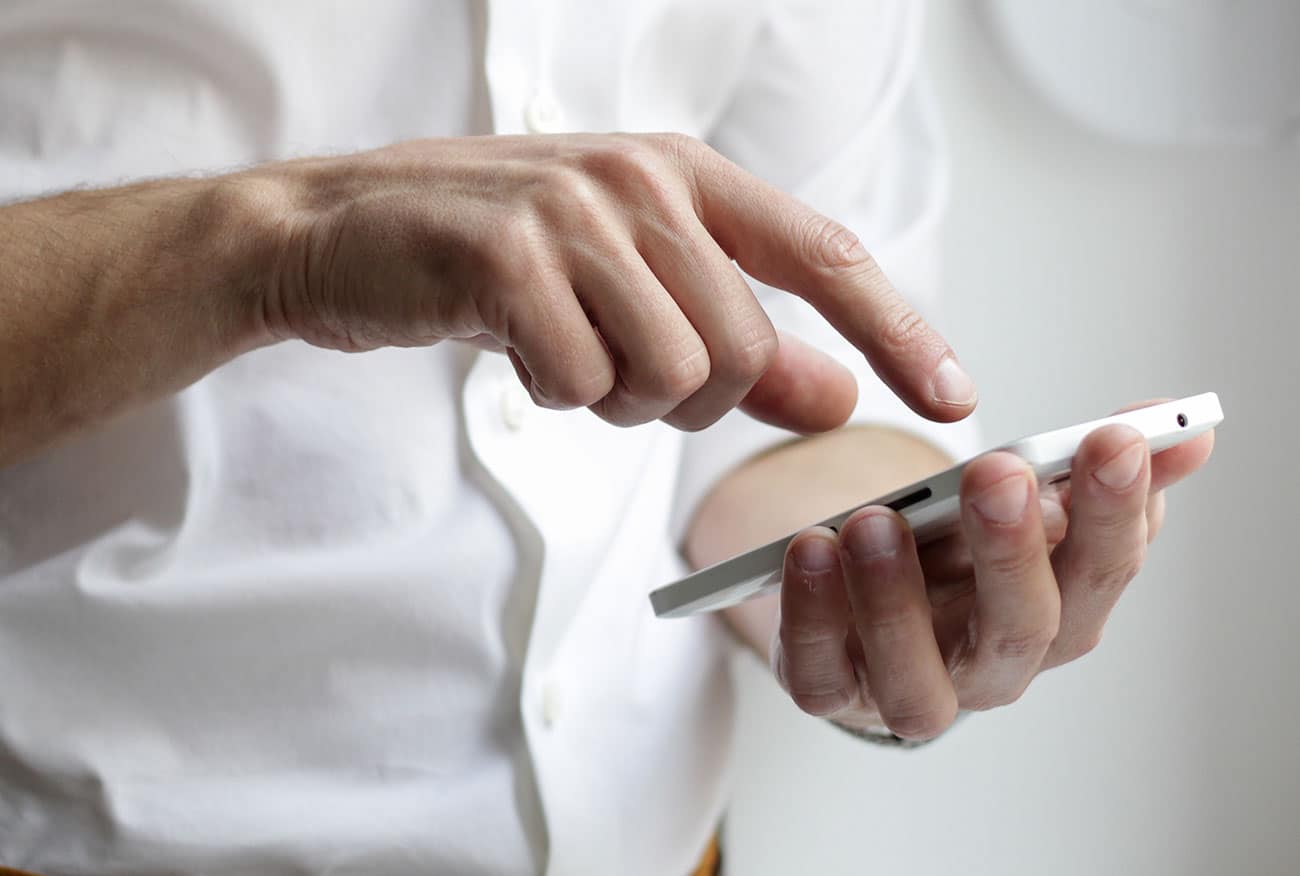man in white button shirt using his smartphone