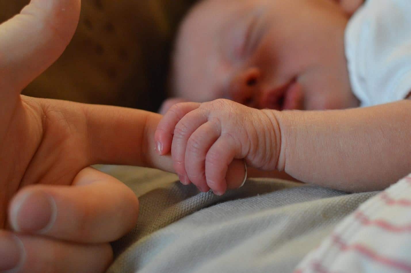sleeping baby holding mother's hand
