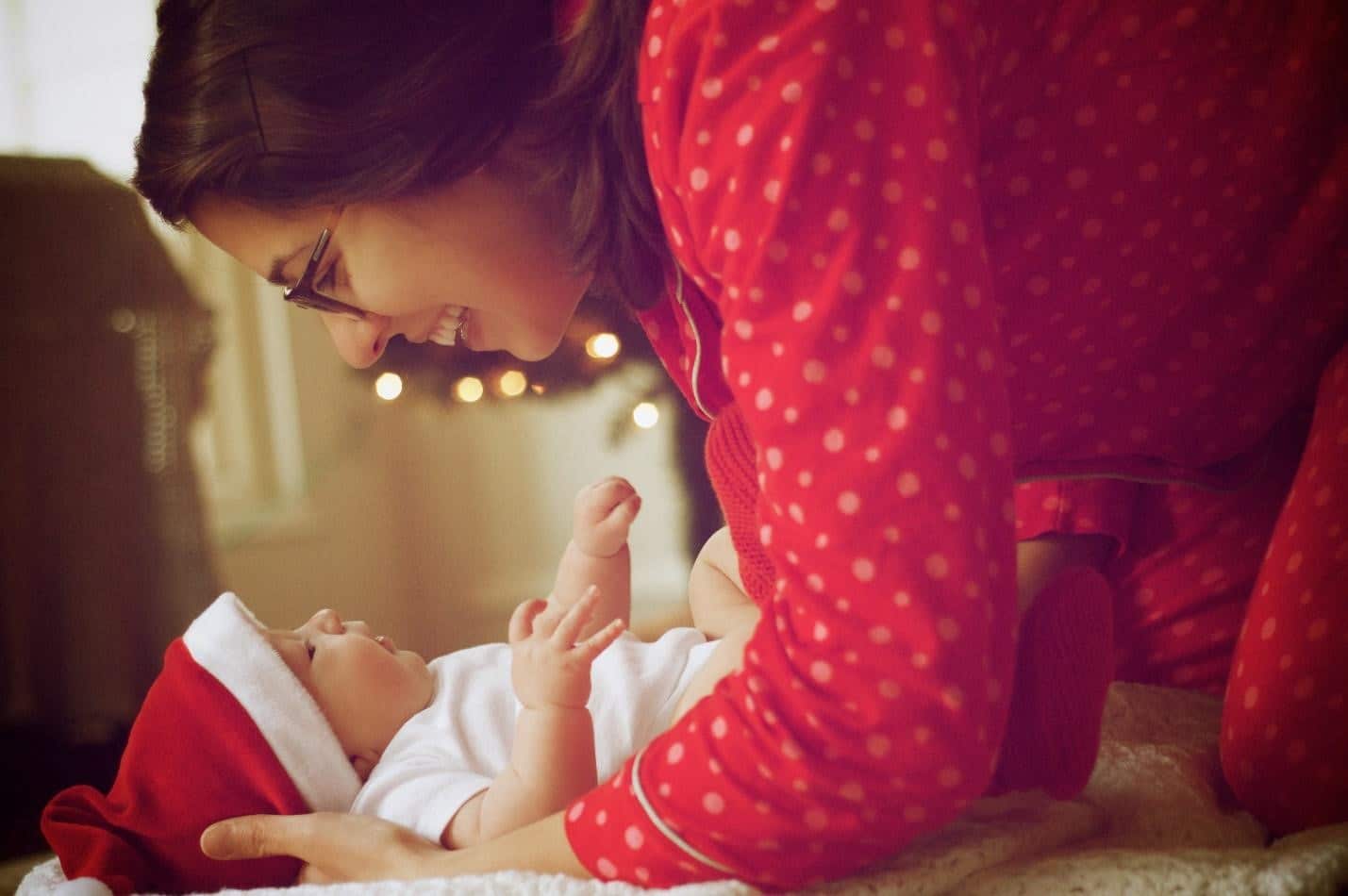 mother in red pajama cuddling with her baby